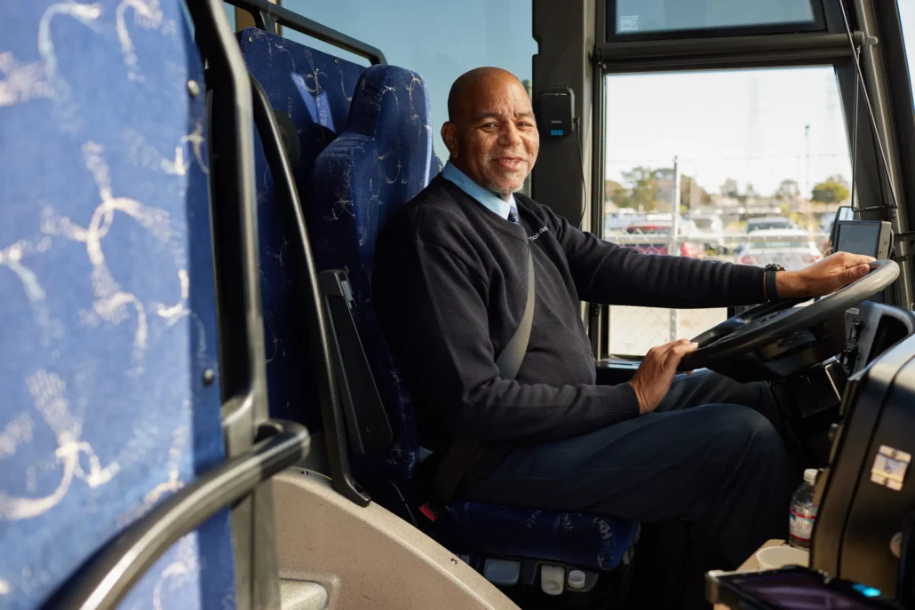 Smiling Marin Airporter driver seated at the wheel of a shuttle bus