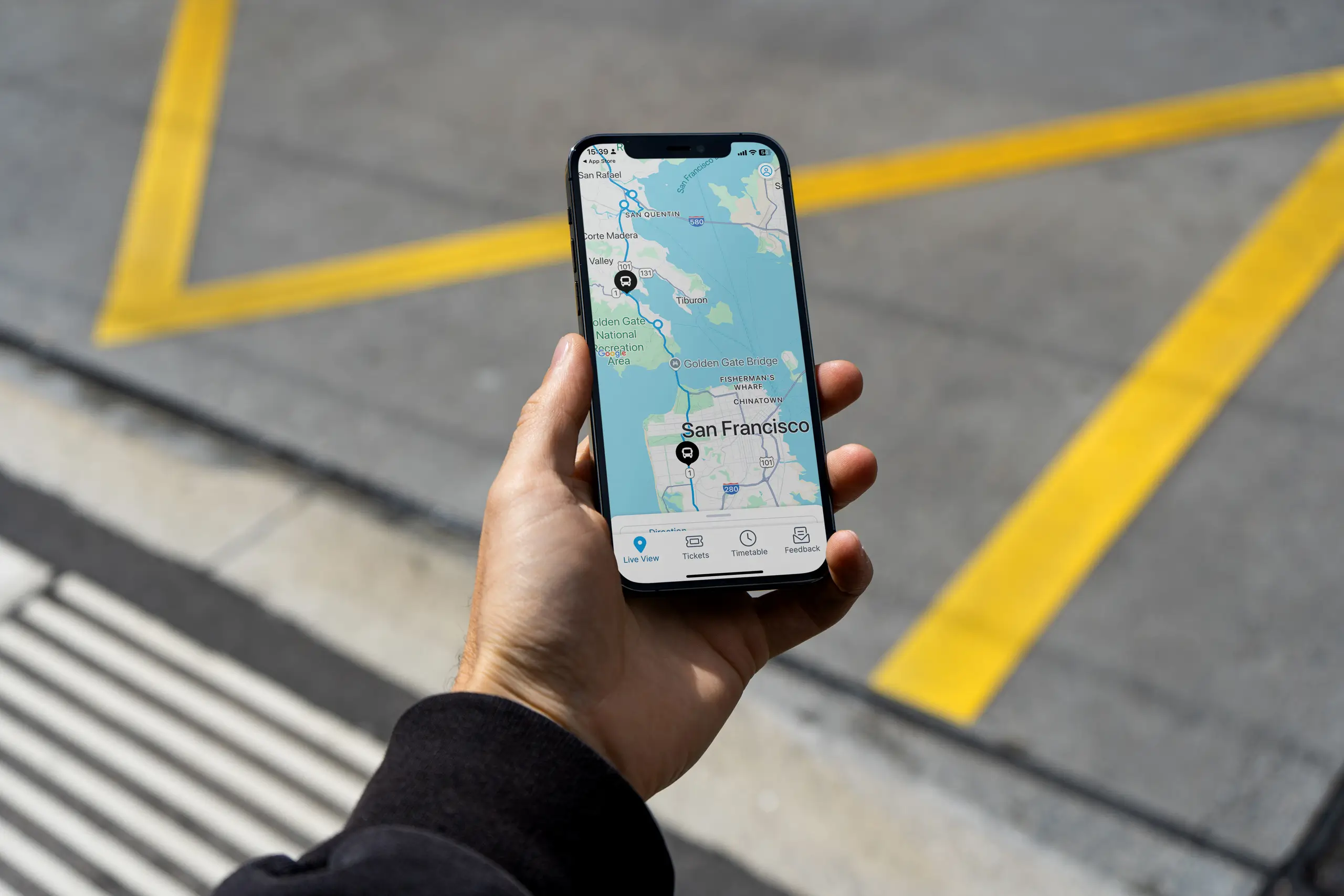 Hand holding a smartphone showing the Marin Airporter app with a live route map centered on San Francisco.
