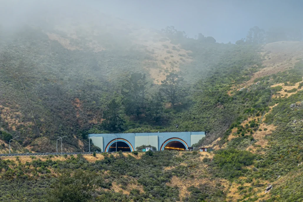 Foggy hillside with vehicles entering the rainbow-adorned Marin Tunnel in California
